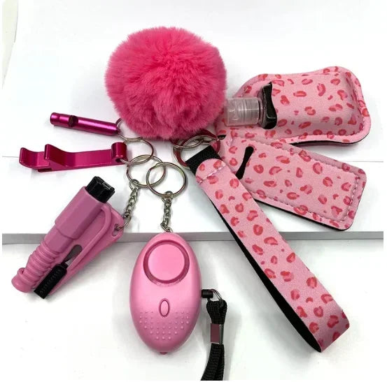 Collection of pink self-defense items including a pepper spray, keychain, and other tools on a white background.