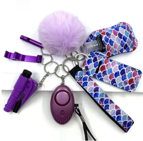 Keychain set with purple safety whistle, pepper spray, and other items on a white background